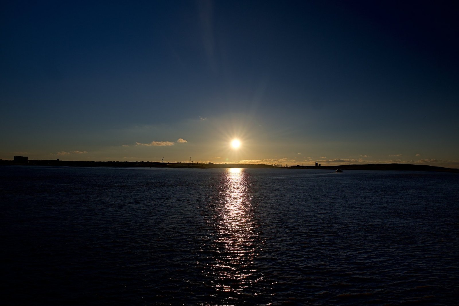 The sun centred low over the Thames, its reflection a straight column of light down the water